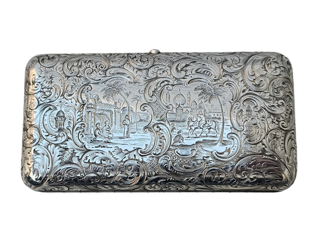 A beautifully engraved, rectangular sterling silver cigar box from the 19th century by Charles Rawlings & William Summers, offered by Seventh Plateau, features intricate floral designs and a scene with figures and camels in a desert, set against a backdrop of domed buildings and palm trees.