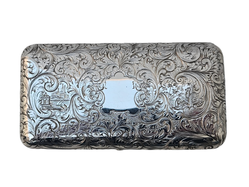 This antique cigar box, crafted by Charles Rawlings & William Summers, is made from sterling silver and features a rectangular design adorned with intricate engravings of floral patterns and decorative swirls. At its center, a blank plaque is framed by scenes of buildings and trees, showcasing the elegance of SEVENTH PLATEAU craftsmanship as it rests smoothly on any surface.