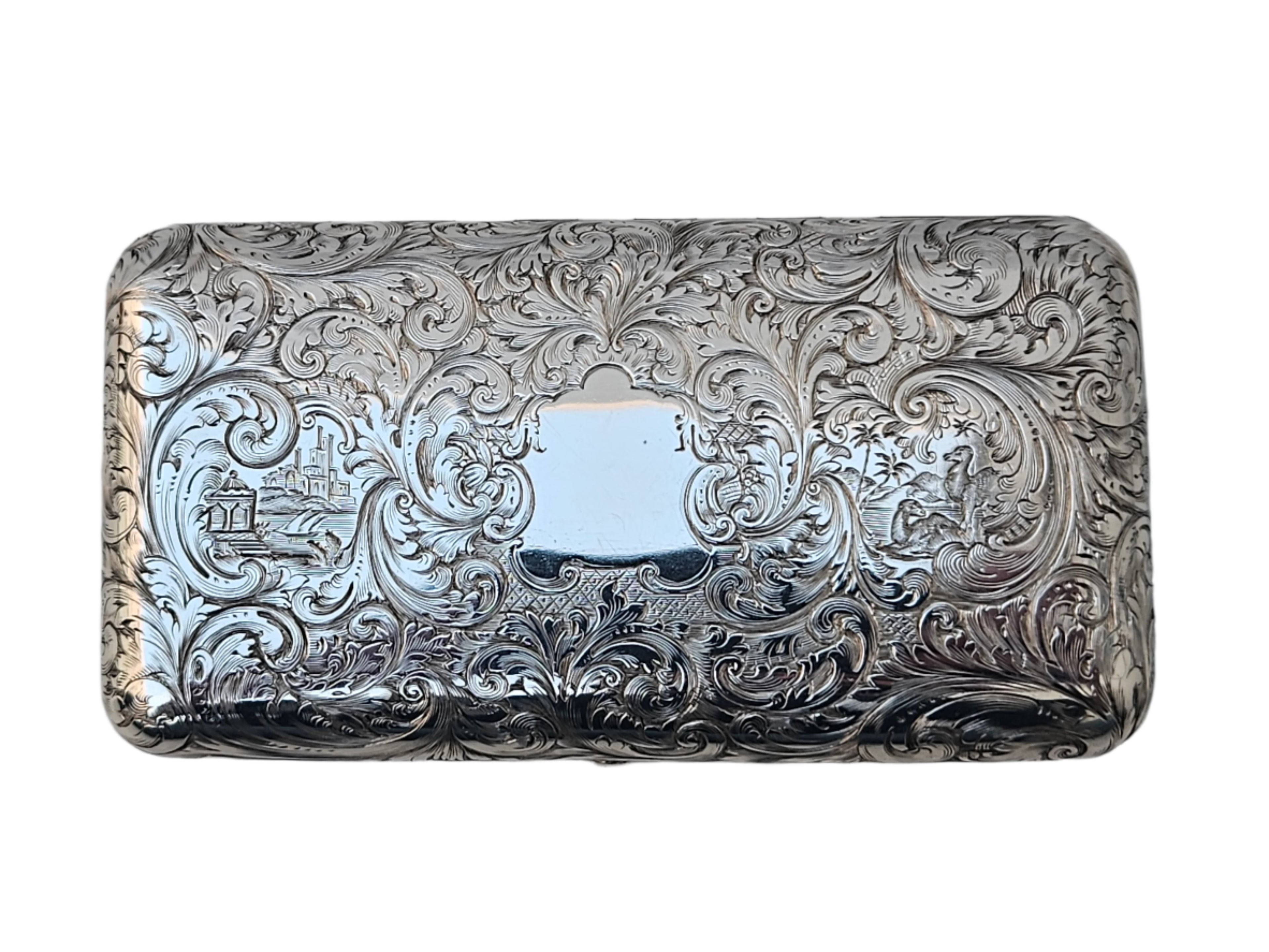 This antique cigar box, crafted by Charles Rawlings & William Summers, is made from sterling silver and features a rectangular design adorned with intricate engravings of floral patterns and decorative swirls. At its center, a blank plaque is framed by scenes of buildings and trees, showcasing the elegance of SEVENTH PLATEAU craftsmanship as it rests smoothly on any surface.
