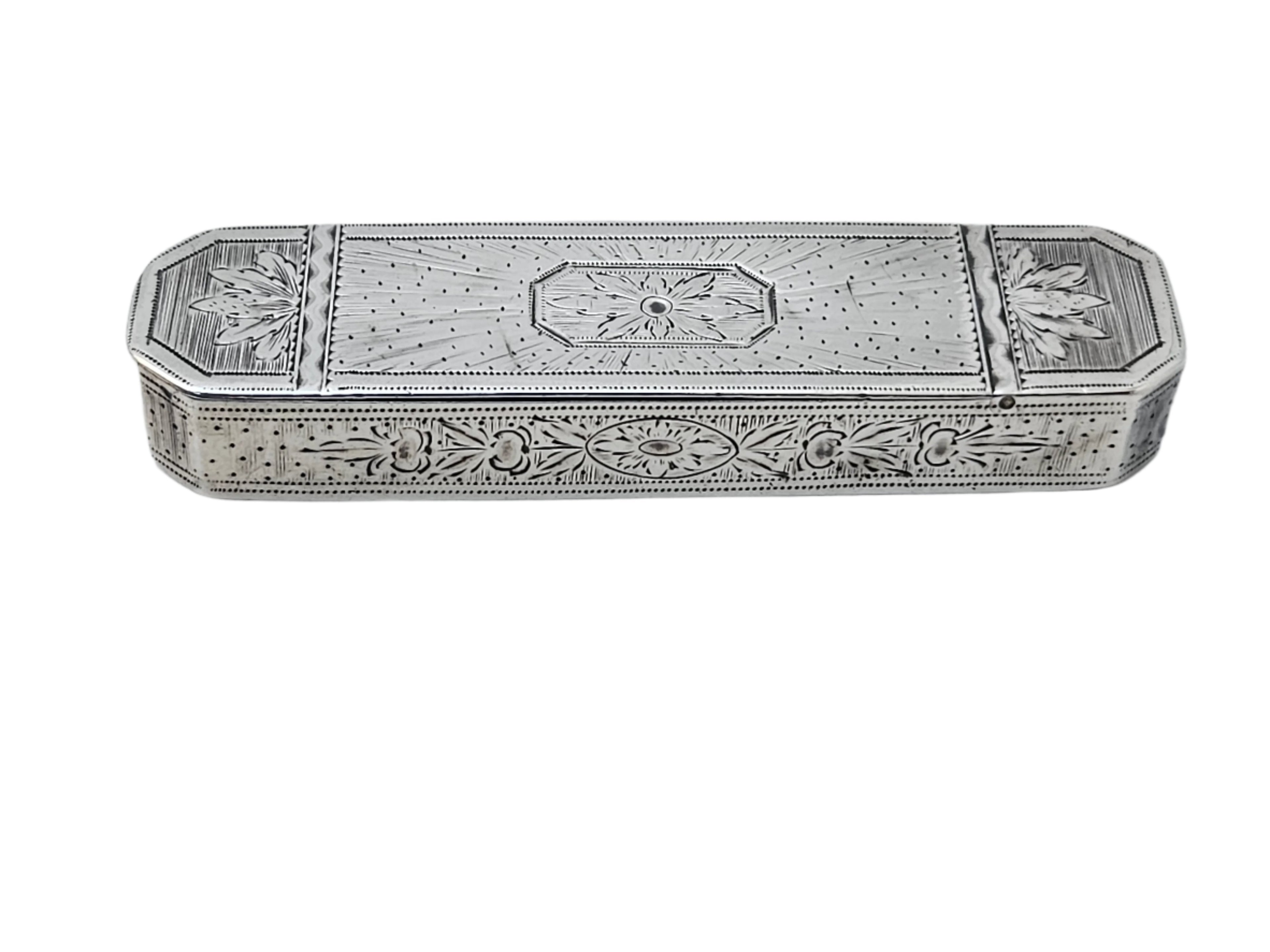 A STERLING SILVER LATE 18TH CENTURY ANTIQUE ENGLISH SAMUEL PEMBERTON TOOTH PICK BOX by SEVENTH PLATEAU rests on a smooth, light-colored surface. This rectangular box features ornate floral and geometric engravings on both the top and sides, highlighting its detailed craftsmanship.
