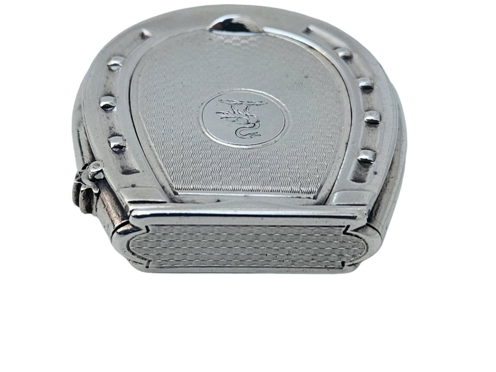 A STERLING SILVER 19TH CENTURY ANTIQUE FRENCH SNUFF BOX & VESTA MATCH CASE by SEVENTH PLATEAU, featuring a horseshoe design on top, rests on a light marble surface. It has a small engraved emblem in the center and intricate detailing around the edges.