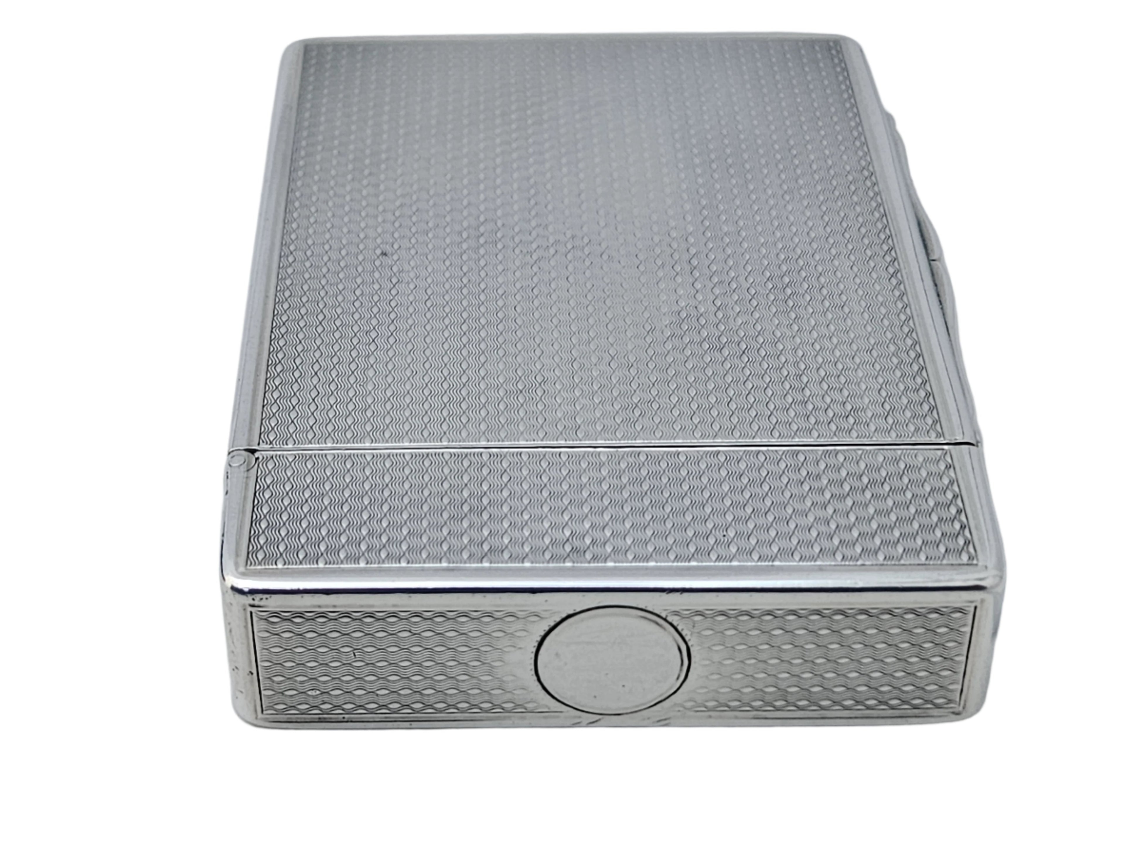 A STERLING SILVER 19TH CENTURY ANTIQUE ENGLISH SNUFF BOX & CALLING CARD CASE by SEVENTH PLATEAU, featuring a textured metal design and circular button on its side, resting on a white surface.